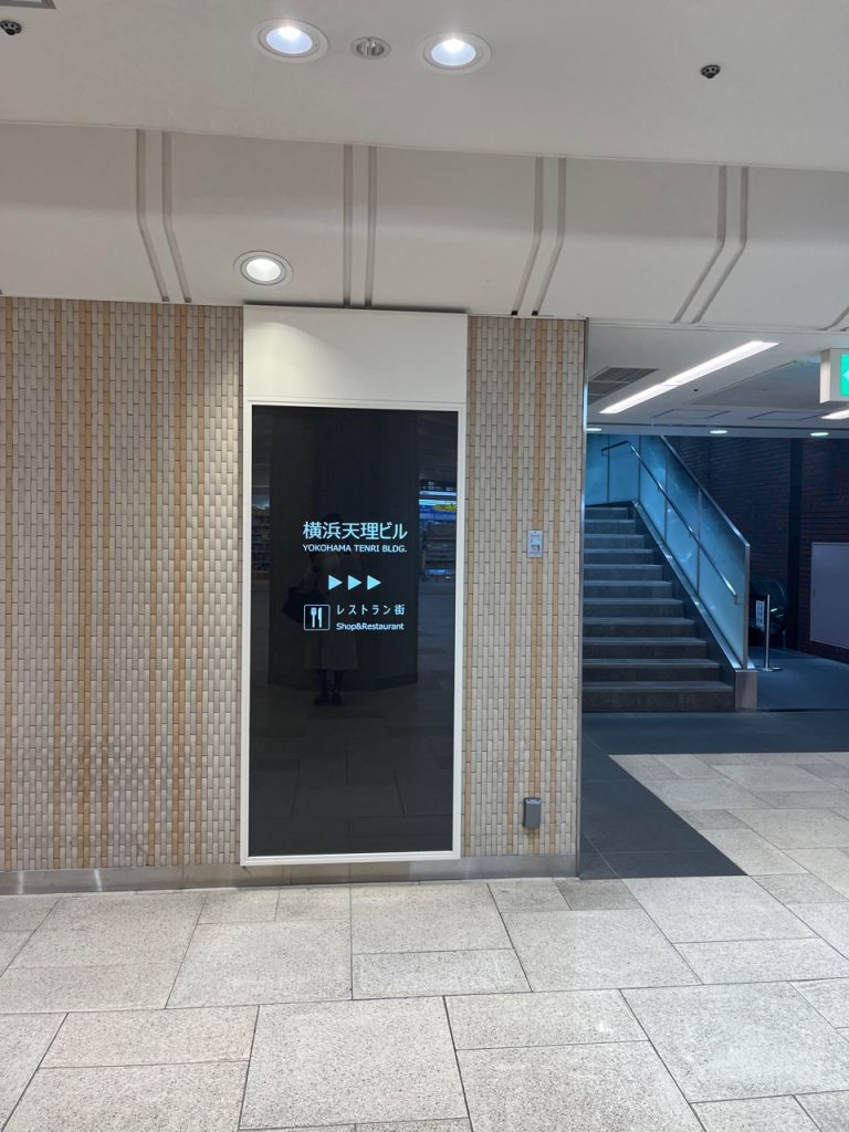 横浜天理ビルの地下入り口案内。青い矢印に従ってレストラン街方面へ