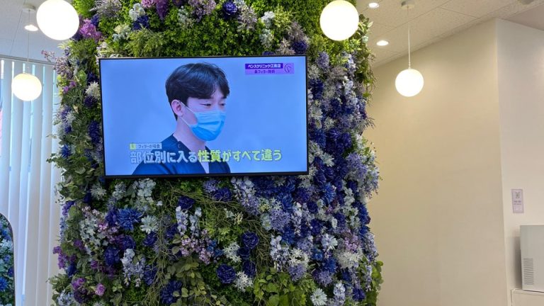 ベンスクリニック横浜の豪華なフラワータワーとモニターがある院内の様子。おしゃれで清潔感のある美容クリニック。